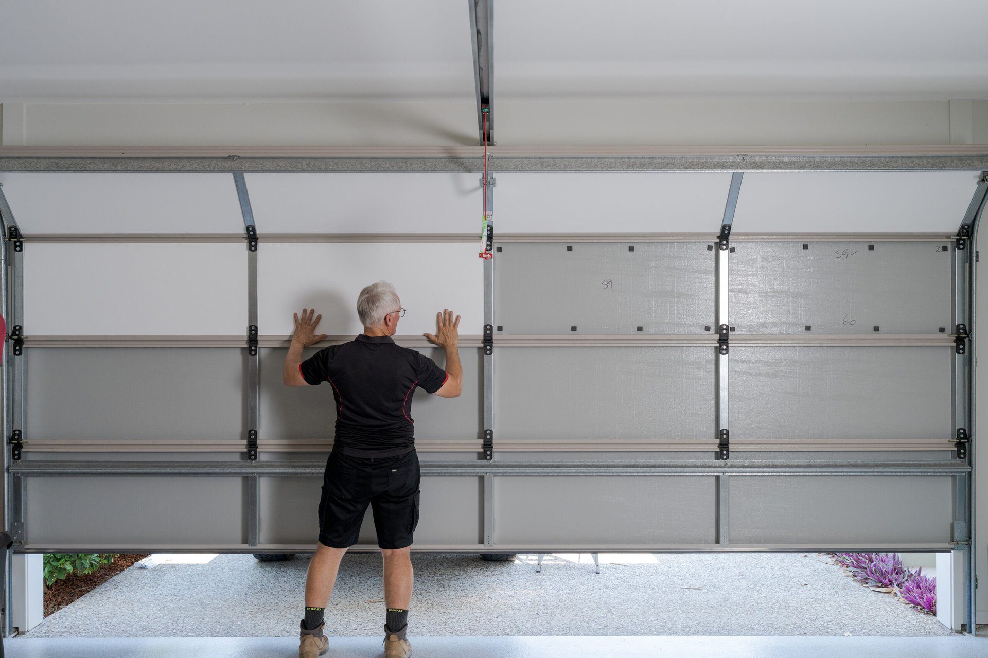 Installer fitting purpose-built garage door insulation panels to reduce summer heat and keep an Australian garage cool without air-conditioning